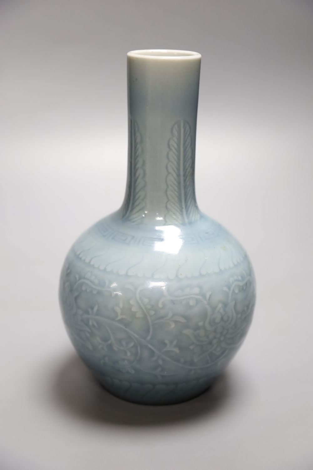 A Chinese bottle vase with carved detail under a pale blue glaze, height 22cm